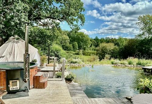 a hot tub on a wooden deck next to a pond at Pearl Of The Prairie in Tollered