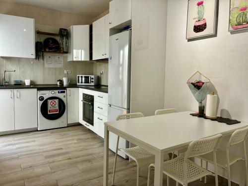 Una cocina con gabinetes blancos y una mesa y sillas. en Amanecer Isleño Habitaciones, en Arrecife