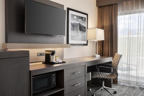 a hotel room with a desk with a tv and a chair at The Kendrick Hotel, an Ascend Collection Hotel in Flagstaff