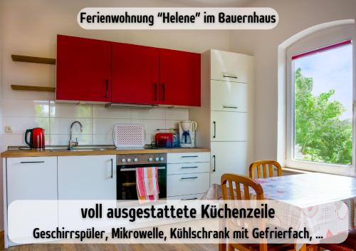 a kitchen with red cabinets and a table at Bauernhof Wisch-Hof - 3 km zum Ostseestrand, 20 km nach Kiel - viele Ausflugsziele in der näheren Umgebung, ideal zum Fahrradfahren in Krokau