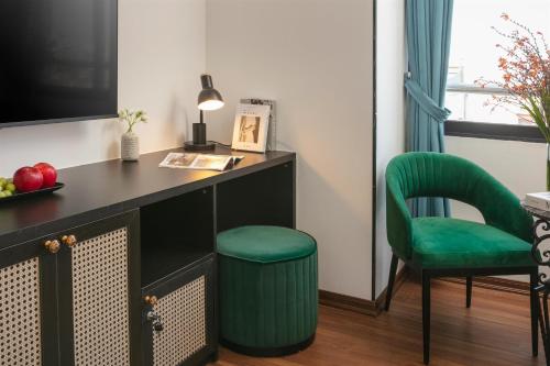 a desk with a green chair next to a table at Hanoi Grandeur Hotel & Spa in Hanoi