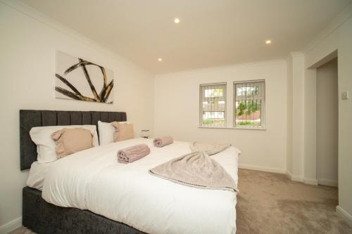 a bedroom with a large white bed with pillows at Luxury 5-Bed, Windsor Sleeps 9, Private Parking in Windsor