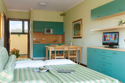a bedroom with a bed and a kitchen with blue cabinets at Residence Spiaggia D'Oro in Desenzano del Garda