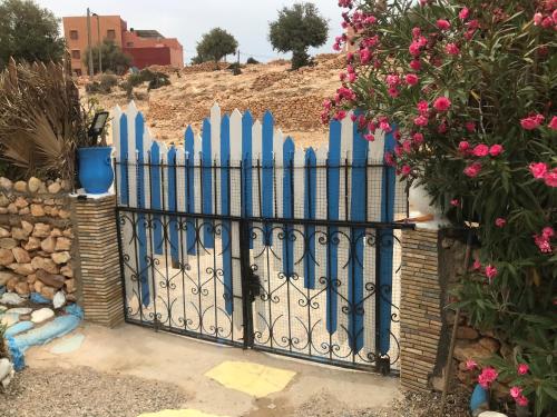 a blue picket fence with pink flowers at Auberge Villa des Jasmins in Aghroude