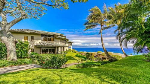 a house with palm trees and the ocean in the background at Kapalua Ridge Villa 1721 in Kapalua