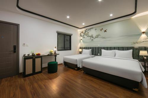a hotel room with two beds and a table at Hanoi Grandeur Hotel & Spa in Hanoi