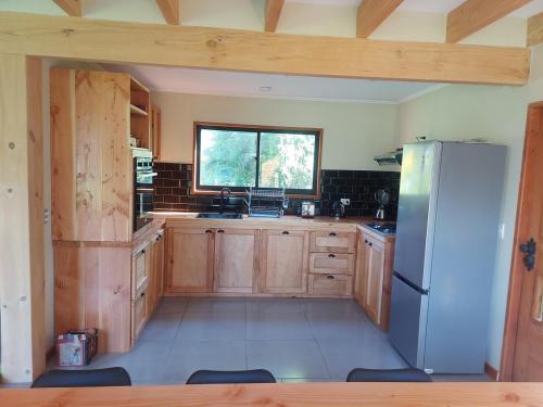 a kitchen with wooden cabinets and a white refrigerator at Beautiful Cabin in Pucon 4D3B in El Cerrillo