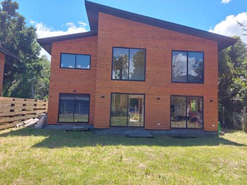 a house with windows on a grass field at Beautiful Cabin in Pucon 4D3B in El Cerrillo