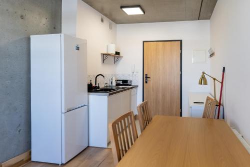 a kitchen with a wooden table and a refrigerator at Apartamenty Przystanek Morska in Gdynia