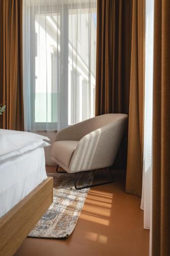 a bedroom with a chair in front of a window at Hotel Bronzo Brno in Brno
