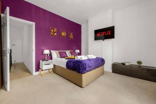 a bedroom with a purple wall and a bed at Bright and Cosy 3-bedroom Home near Manchester - Free parking - Sleeps 6 in Manchester