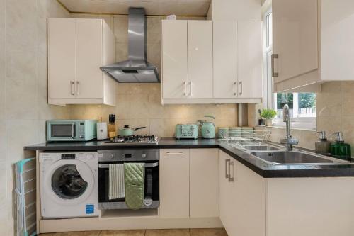a kitchen with white cabinets and a dishwasher at Bright and Cosy 3-bedroom Home near Manchester - Free parking - Sleeps 6 in Manchester