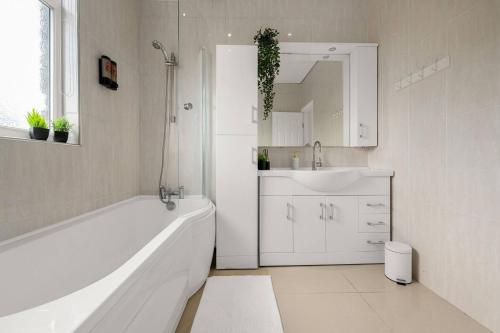 a white bathroom with a tub and a sink at Bright and Cosy 3-bedroom Home near Manchester - Free parking - Sleeps 6 in Manchester