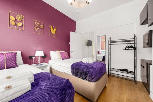 two beds in a room with purple walls at Bright and Cosy 3-bedroom Home near Manchester - Free parking - Sleeps 6 in Manchester