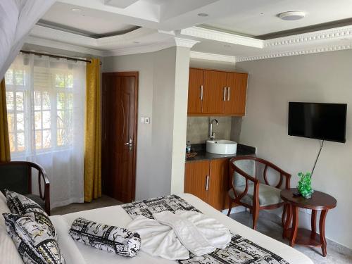 a bedroom with a bed and a table and a kitchen at GreenHaven Siaya Cottages in Siaya
