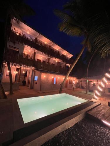 a swimming pool in front of a building at night at Tides Mirissa Beach Hostel in Mirissa