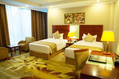 una camera d'albergo con 2 letti e una scrivania di Jupiter International Hotel - Cazanchis ad Addis Abeba
