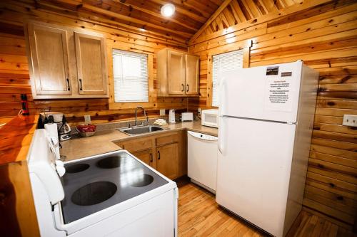 a kitchen with wooden cabinets and a white refrigerator at The Cabins at Pine Haven - Beckley in Beaver