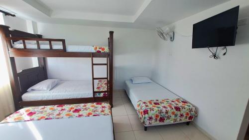 a room with two bunk beds and a flat screen tv at Hotel La Santamaria - Montenegro Quindío in Montenegro