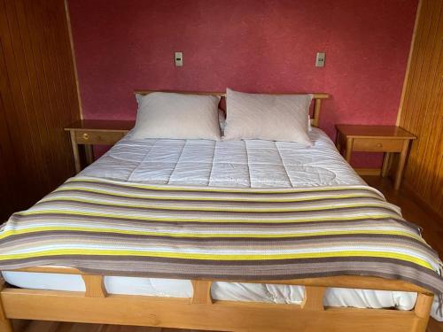 a large bed in a room with two tables at Hospedaje BoppHouse in Coihaique