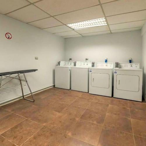 a laundry room with four washing machines and a table at Hostal PdeV in Concepción