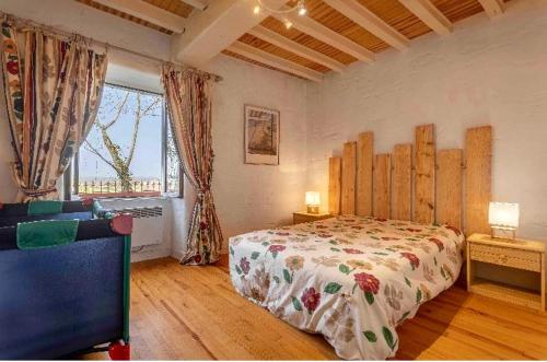 a bedroom with a bed and a large window at Bastide piscine, pétanque, salle de jeux et spa in Guiche