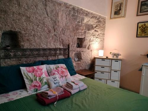 a bedroom with a green bed with two pillows and flowers at Apartments Aurora Delle Rose in Assisi