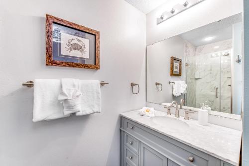 a bathroom with a sink and a mirror at Palm Court Yacht Club #303 in Fort Walton Beach