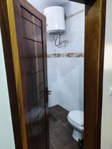 a bathroom with a toilet and a wooden door at Grand Studio avec toutes les commodités in Dakar