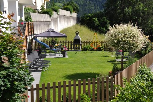 a garden with a playground with chairs and an umbrella at Gschlössle Ferienwohnungen in Jerzens