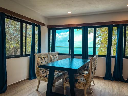a dining room with a table and chairs and windows at Hotel Glamping Horizonte Maya in Chetumal