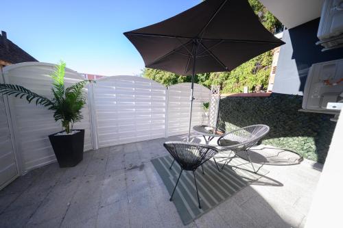 a patio with an umbrella and a table and chairs at Apartman Ena in Vinkovci