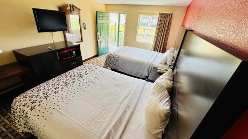 a hotel room with two beds and a television at Garden Inn and Suites near Callaway Gardens Pine Mountain in Pine Mountain