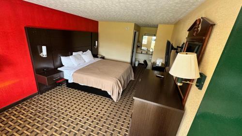 a hotel room with a bed and a lamp at Garden Inn and Suites near Callaway Gardens Pine Mountain in Pine Mountain