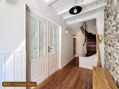un pasillo con paredes blancas y una puerta y escaleras en La Rose du Roc - Maison 4 niveaux, terrasse vue mer, en Granville