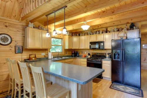 a kitchen with a black refrigerator and wooden cabinets at Lakefront Hazelhurst Cabin Dock and Pool Table in Hazelhurst