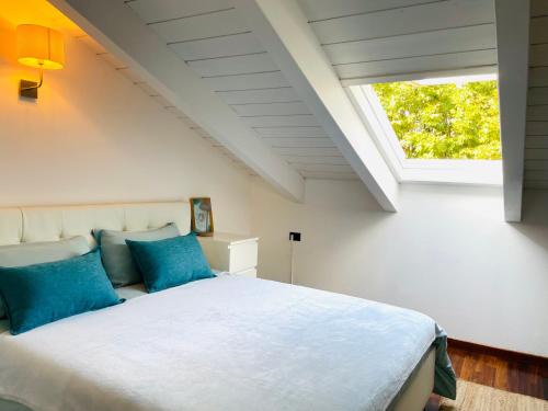 a bedroom with a bed with blue pillows and a window at La finestra sul lago in Malgrate