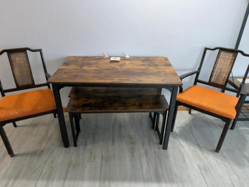 a wooden table and two chairs with orange seats at Gordie's Inn & Suites in Alert Bay