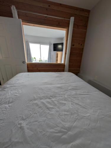 a bedroom with a large white bed with a window at Gordie's Inn & Suites in Alert Bay