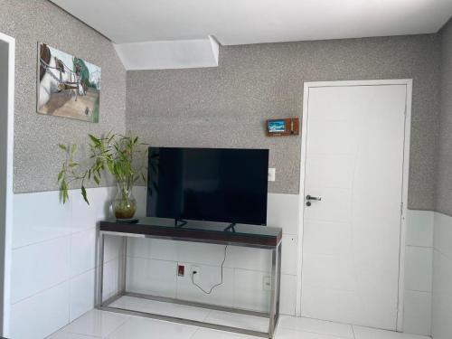 a living room with a tv on a wall at Cantinho da Barra in Barra dos Coqueiros