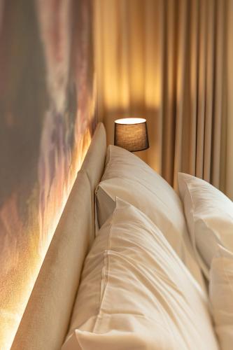 a bed with white pillows and a lamp at Hotel Bronzo Brno in Brno