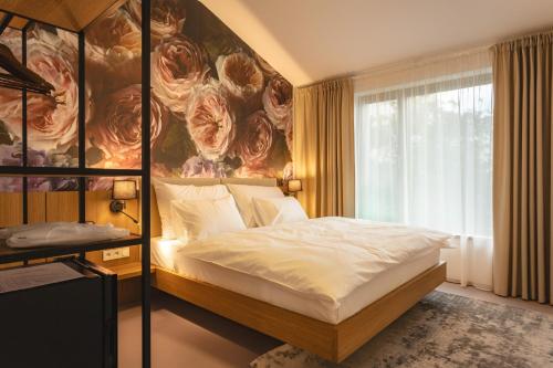 a bedroom with a bed with a large flower painting on the wall at Hotel Bronzo Brno in Brno