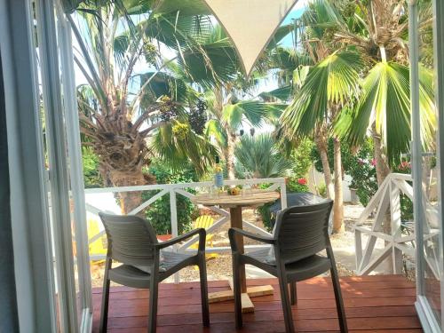 a table and chairs on a porch with palm trees at The Rocks Residence, apartment 2 of total 2 in Paradera