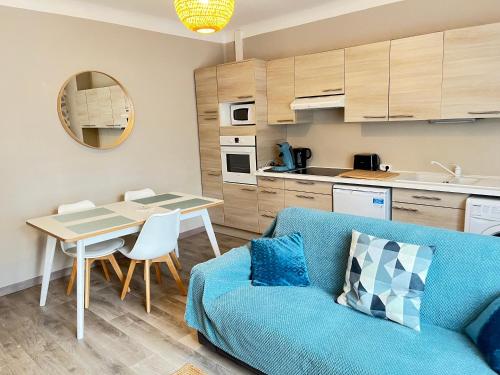 a living room with a blue couch and a table at La Falaisienne - Appartement pour 4 au cœur de Falaise - "Larès" in Falaise