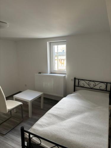 a bedroom with a bed and a chair and a window at Siegbacher Privatzimmer in Eisemroth