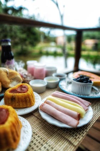 a table with plates of hot dogs and pastries at Chalés Villa Caravaggio - by Easy Hotéis in Santa Teresa