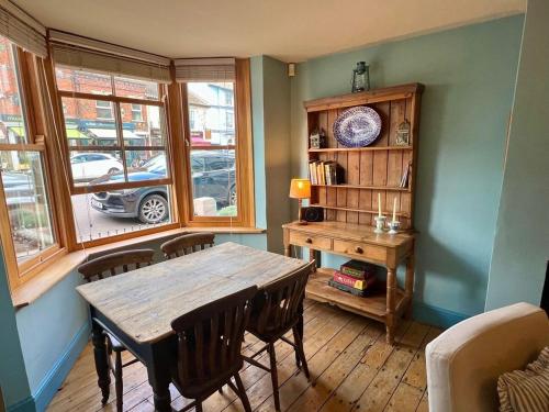 a dining room with a wooden table and a book shelf at Pilots House Aldeburgh in Aldeburgh