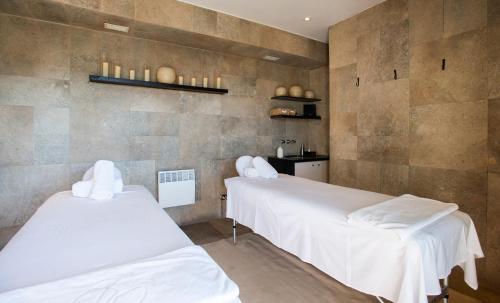 two beds in a room with white sheets at Hotel Casa Higueras in Valparaíso