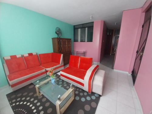 a living room with two red couches and a table at Piso de 2 camas in Moyobamba