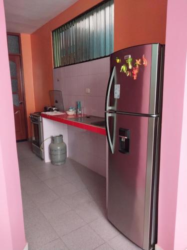 a kitchen with a stainless steel refrigerator and orange walls at Piso de 2 camas in Moyobamba